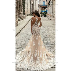 Champagne mermaid wedding dress with off-the-shoulder neckline, intricate lace applique, and a floor-length tulle train.