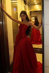 Red satin strapless prom dress with ruched bodice photographed in a mirror