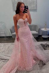 Blush pink mermaid prom dress with sheer lace corset bodice and tulle overskirt train, front view