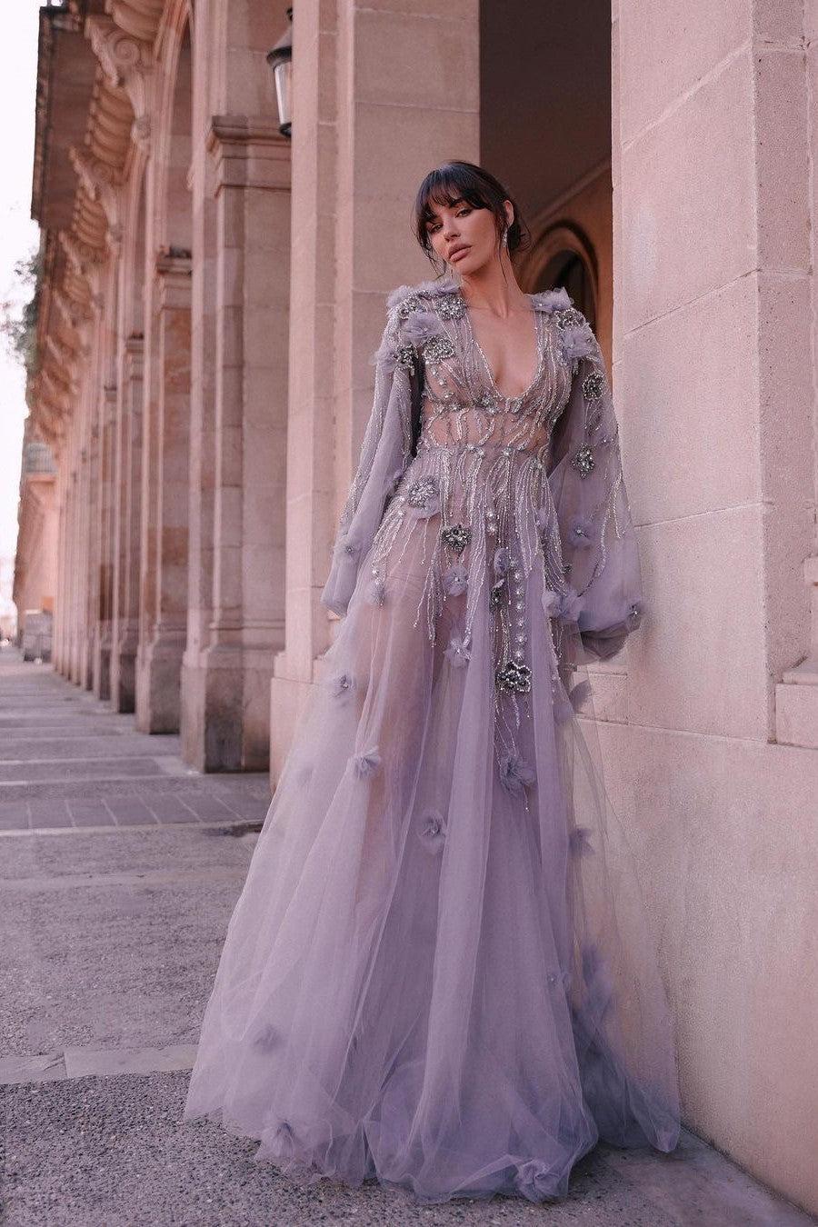Model beside a stone colonnade showing the illusion bodice beadwork and sweeping floor-length tulle skirt of the prom dress