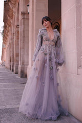 Model beside a stone colonnade showing the illusion bodice beadwork and sweeping floor-length tulle skirt of the prom dress