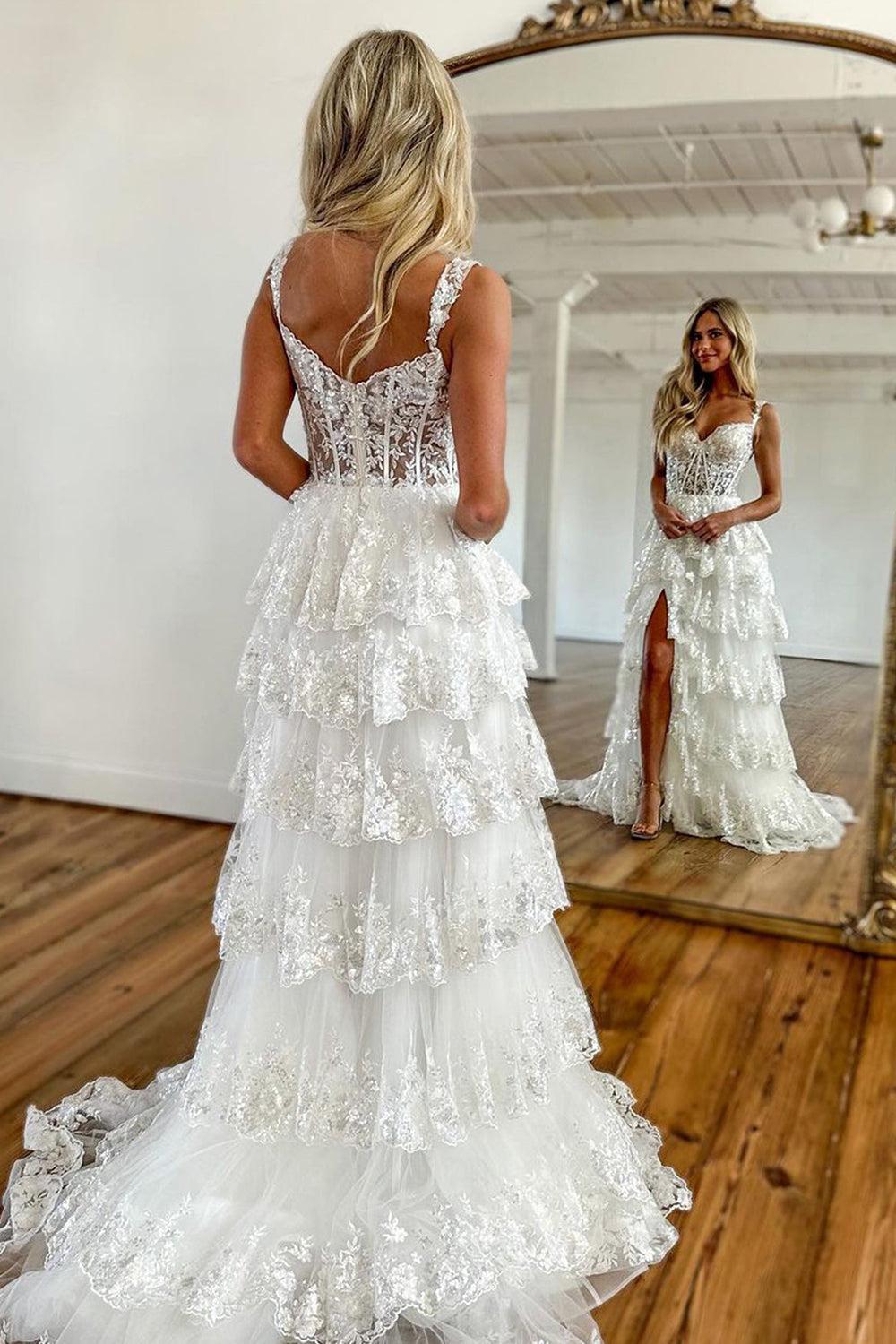 Ivory lace wedding dress with a corset bodice, tiered tulle skirt, and high leg slit, reflected in a mirror.