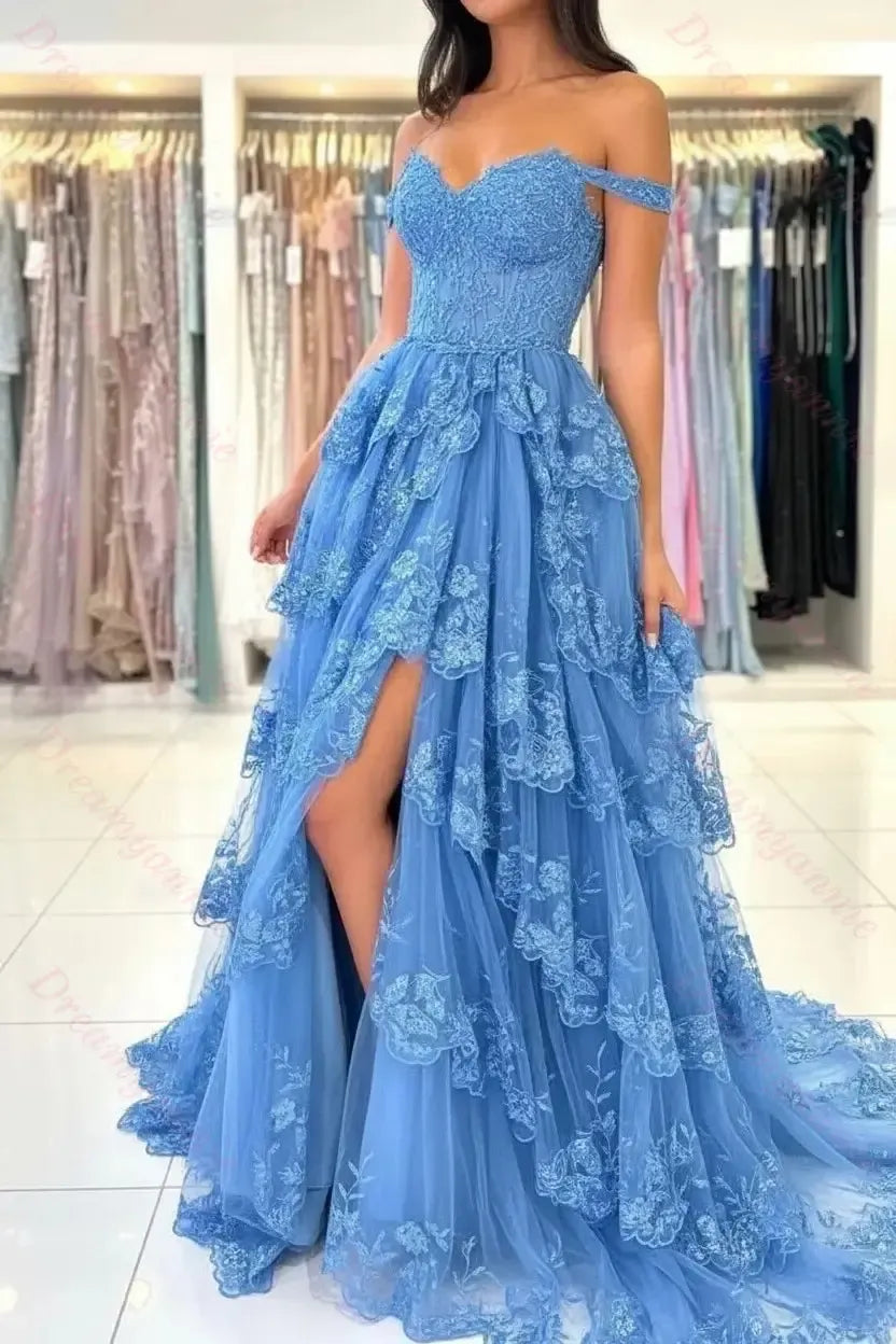 Blue off-the-shoulder bridal dress featuring tiered lace, tulle fabric, and a high-slit skirt in a boutique setting.