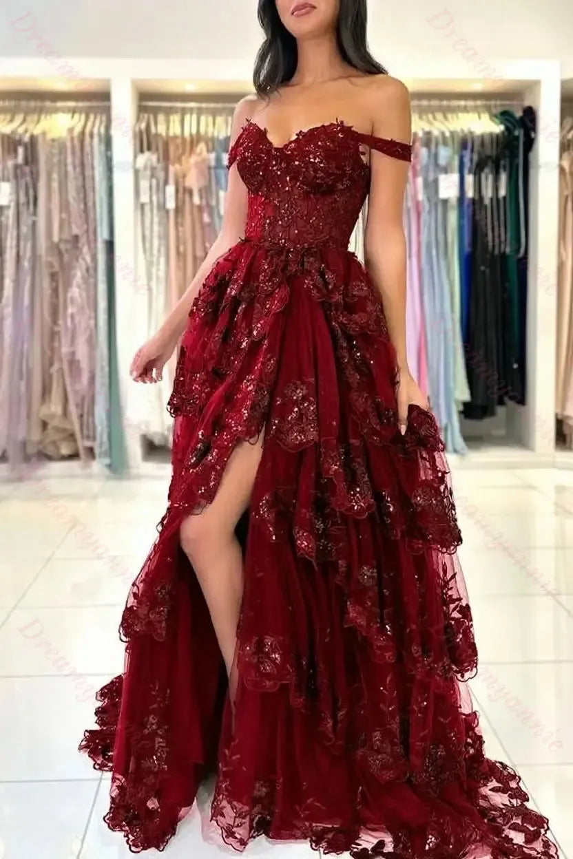 Off-the-shoulder burgundy lace wedding dress with a tiered tulle skirt, sequin embellishments, and a high leg slit.
