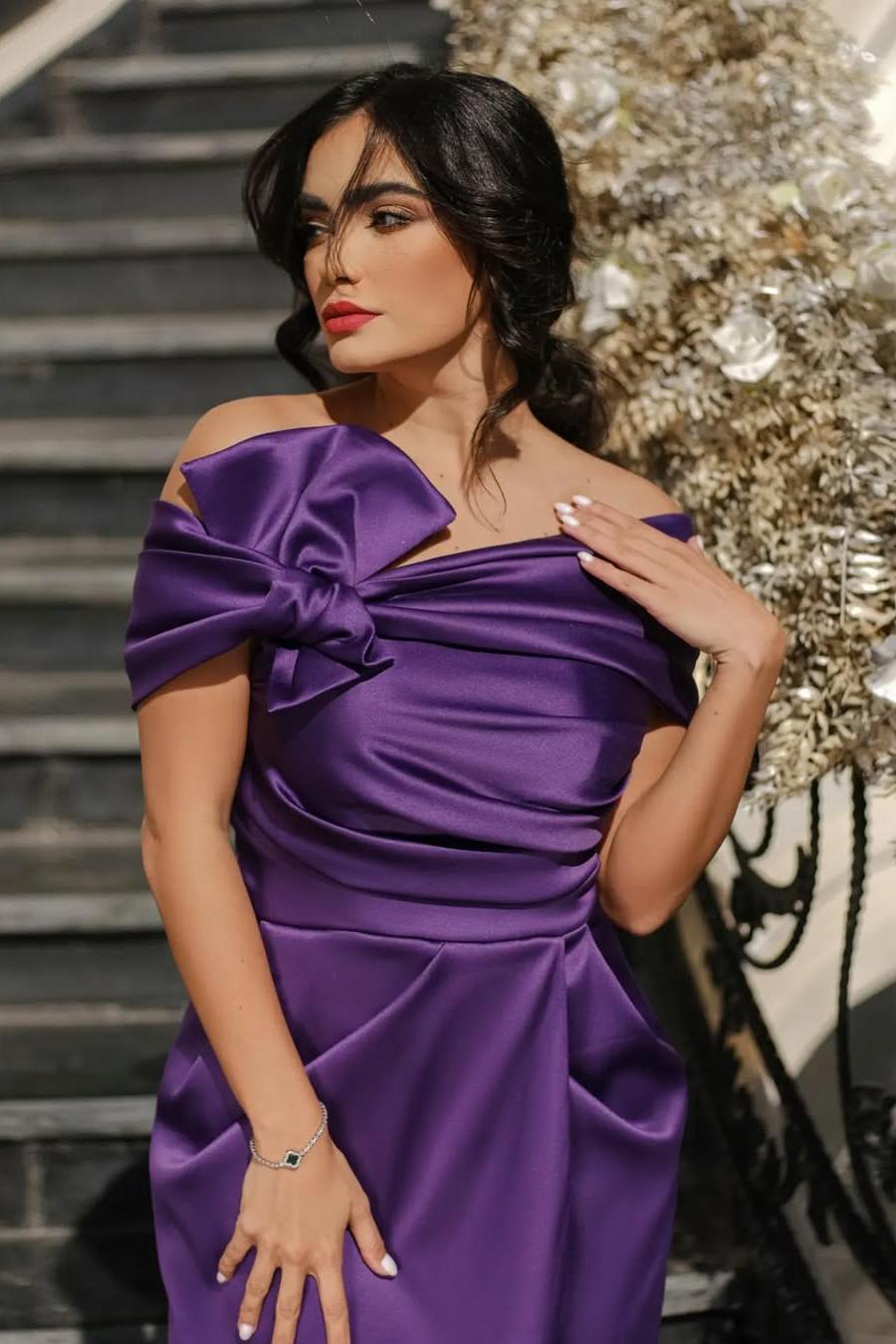 Close-up of the purple satin prom dress showing the asymmetric bow shoulder and ruched bodice
