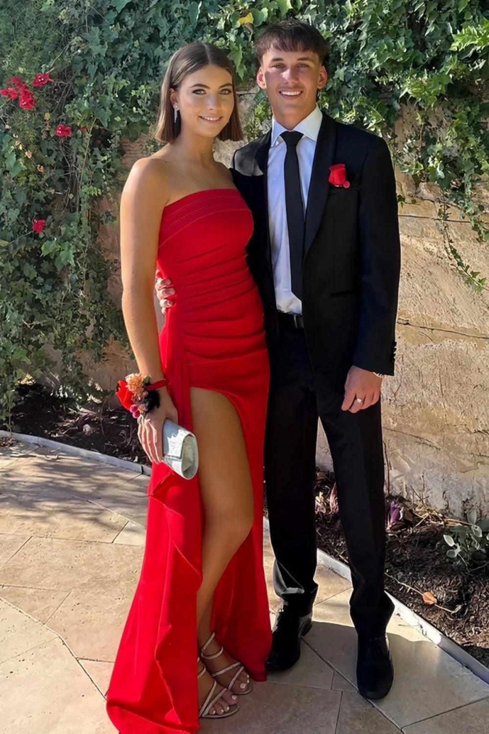 Red strapless mermaid prom dress with high slit worn for an outdoor prom photo