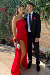 Red strapless mermaid prom dress with high slit worn for an outdoor prom photo